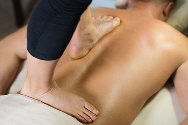 A therapist applying firm pressure along a guest's back