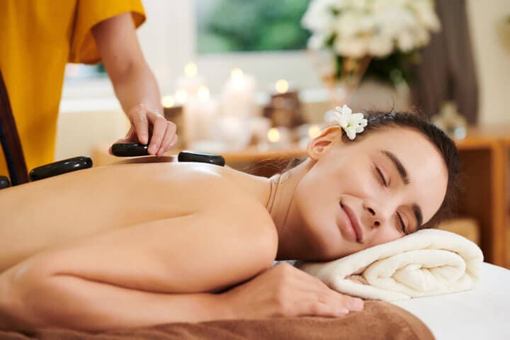 A therapist placing warm stones along a guest's back